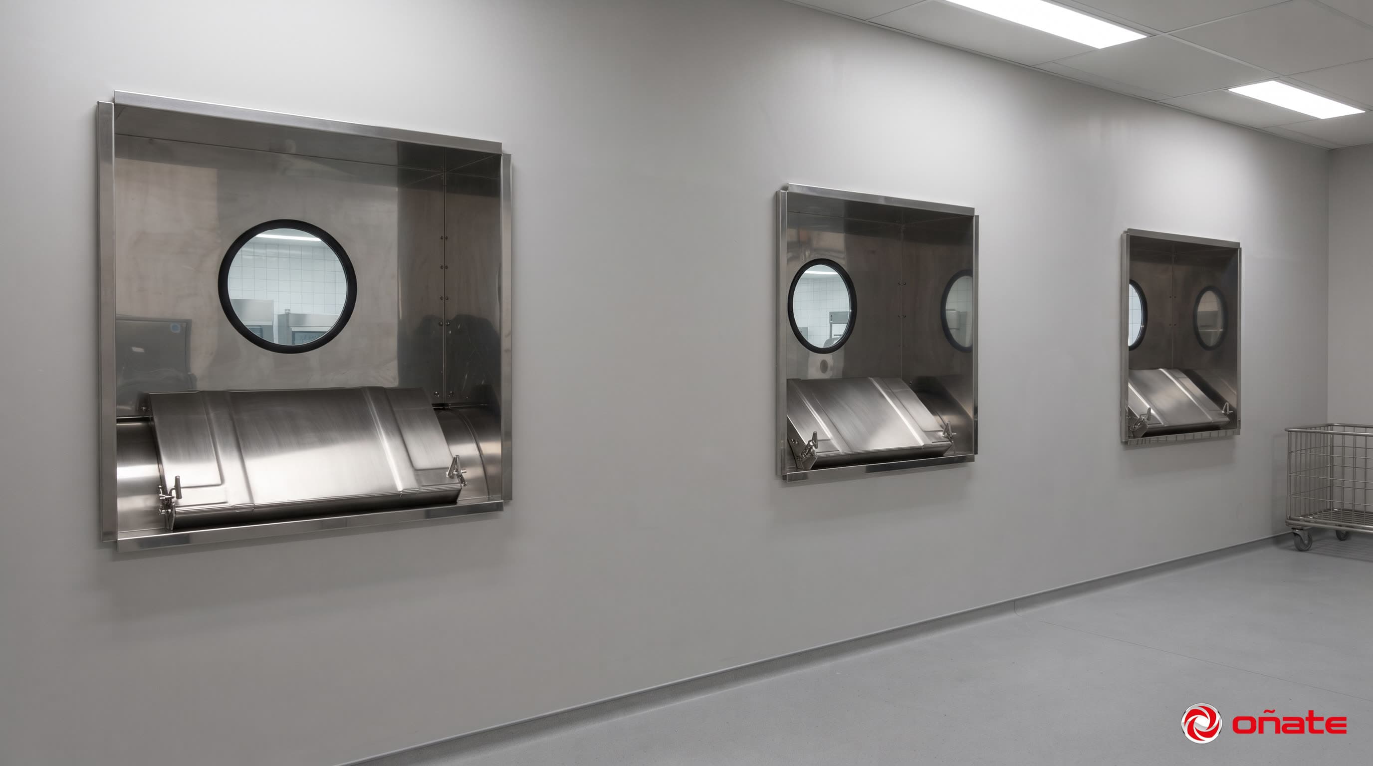 Lavadoras con barrera sanitaria Oñate instaladas en el tabique divisorio de una lavandería hospitalaria, vistas desde la sala limpia con los visores de vidrio